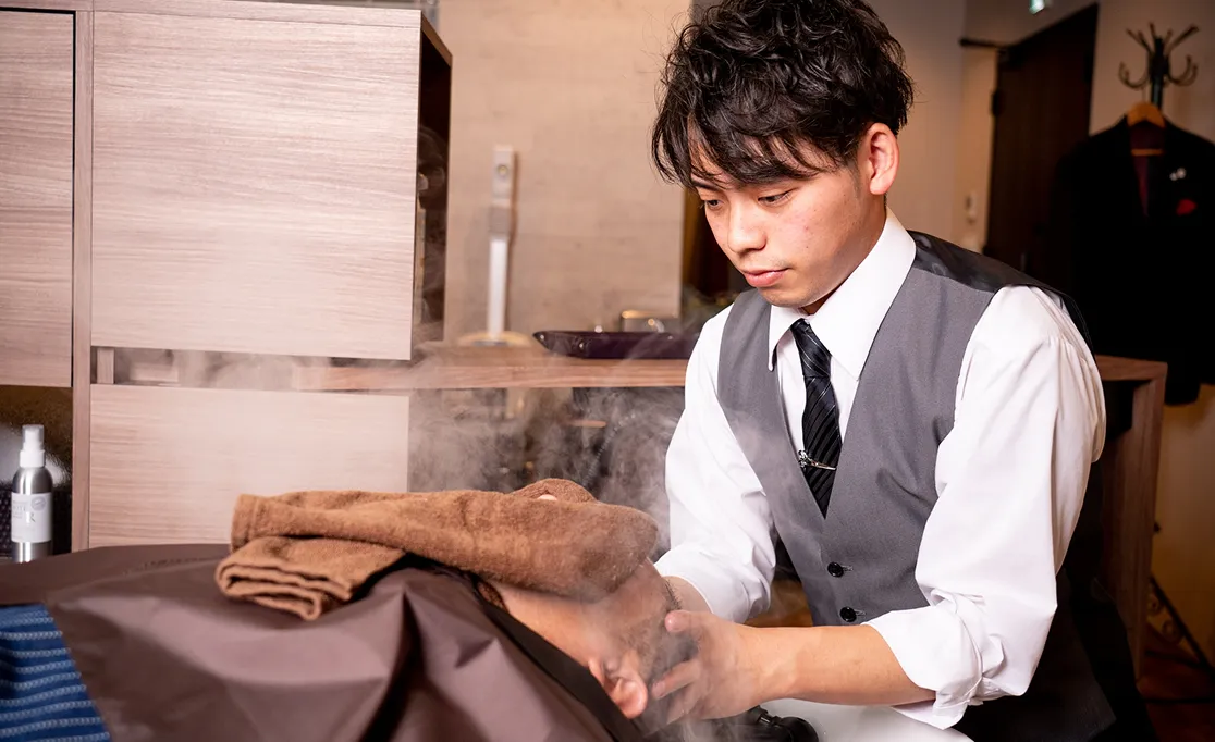 札幌の高級理容室で湯気を立てながらお湯を使ったヘッドスパを施す理容師