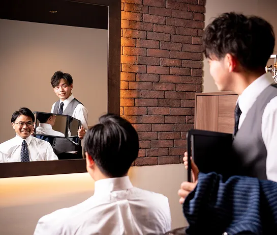 札幌の高級理容室で、仕上がりを鏡で確認し笑顔を見せるビジネスマンと理容師