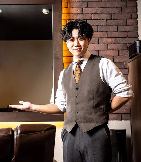 札幌の高級理容室で施術席を案内する笑顔の理容師と上質な店内
