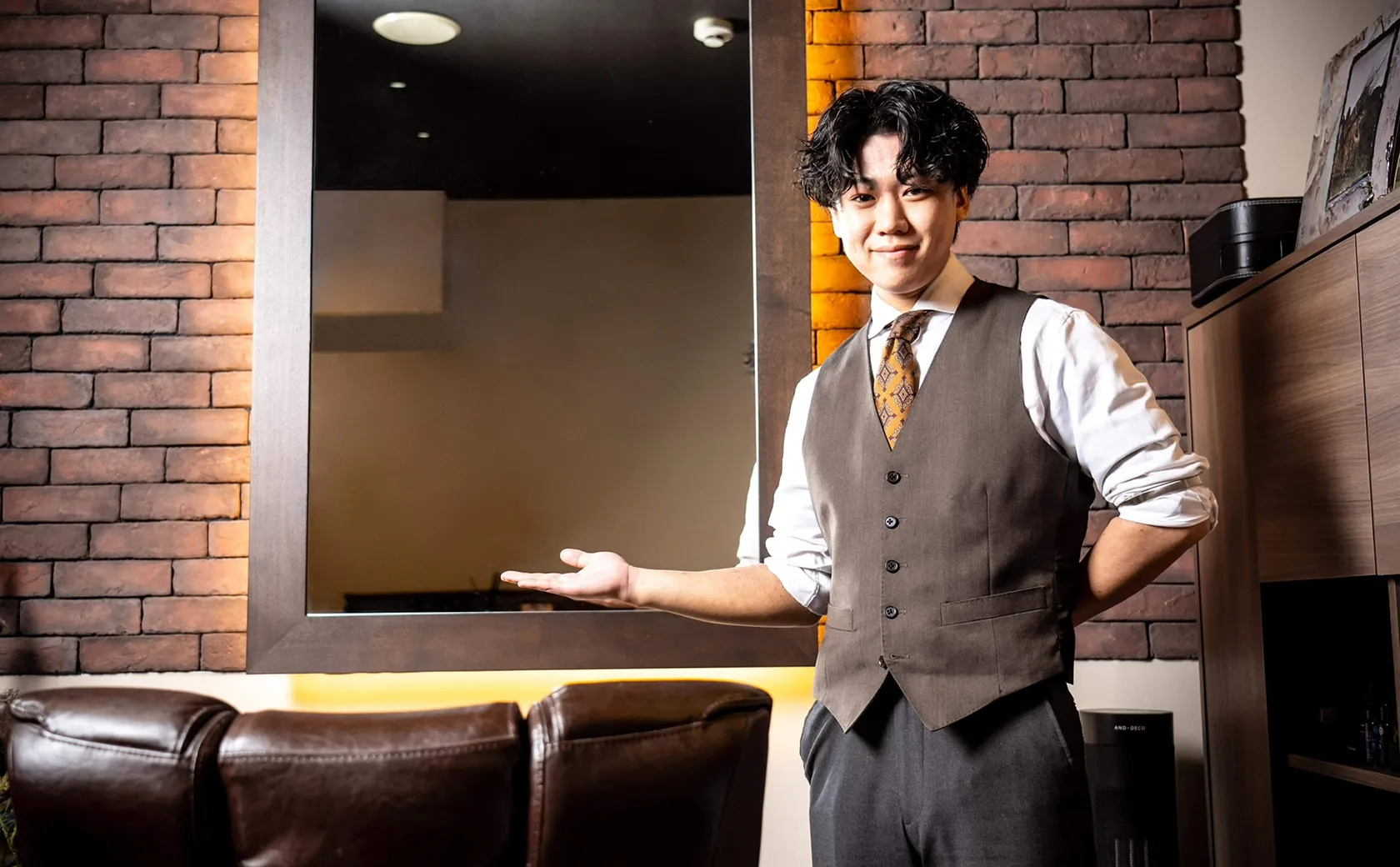 札幌の高級理容室で施術席を案内する笑顔の理容師と上質な店内